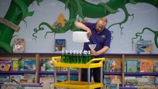 Site manager Mark Lee fills bottles of hand sanitizer at Queen