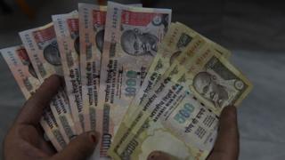 Индийский житель держит 500 и 1000 рупий банкноты