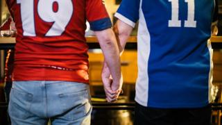 Dois torcedores de mãos dadas