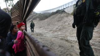 Niña migrante en una sección de la valla fronteriza en Tijuana.