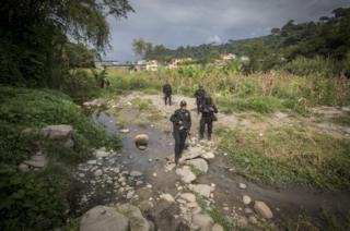 Policías cruzando un riachuelo.