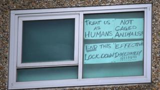 Un cartel en la ventana de una de las unidades bloqueadas dice: Tratar como humanos, no como animales enjaulados.