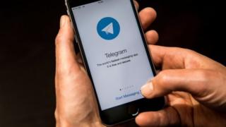 Mobil telefonida Telegram dan foydalanayotgan inson