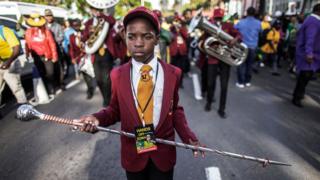 A child leads a brass band on June 8, 2018 outside the High Court, in Durban, as he takes part in a rally in support of former South African president Jacob Zuma.