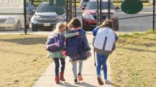 School children wearing facemasks walk outside Condit Elementary School in Bellaire, outside Houston, Texas