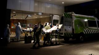 A patient is transported on to an ambulance outside an aged care home