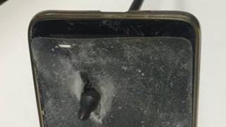 The man's damaged phone seen with an arrow through it