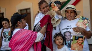A family holds signs of a missing loved one during a march in el Fuerte, Sinaloa