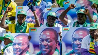 Zanu-PF supporters in Zimbabwe hold up pictures of President Emmerson Mnangagwa at a rally on 28 July 2018