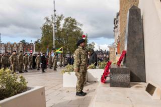 A soldier stands in front of a war memorial during a military service