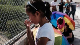 A Honduran girl waits with her family along the border bridge after being denied entry from Mexico into the US