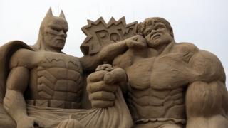 Batman and the Hulk sculpture made out of sand