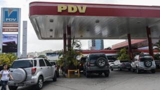 Imagem mostra carras em fila para serem abastecidos em posto de combustíveis com a bandeira da estatal venezuelana PDV