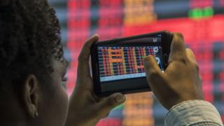 A visitor take pictures of a board at the Sao Paulo Stock Exchange (B3), in Sao Paulo, Brazil, on May 18, 2017. Brazilian financial markets plummeted on opening Thursday in the wake of a bombshell report that President Michel Temer approved paying hush money to a corrupt politician. T