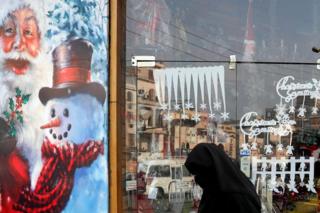 An Egyptian woman wearing a full veil walks in front of a Christmas decorated shop in Cairo, Egypt - Monday 3 December 2018
