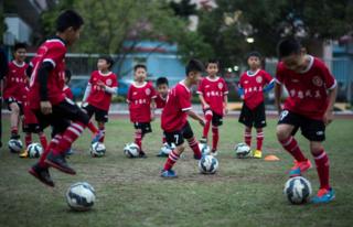 Meninos treinam em aula de futebol em Guangzhou
