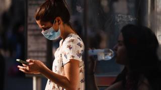 Woman wearing a mask, checking a phone