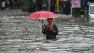 Uma caminhada da menina ao longo de uma rua inundada apÃ³s o mercado de Gandhi dos chuveiros de chuva pesada, Sion o 1Âº de julho de 2019 em Mumbai, Ãndia.  Chuvas fortes nos Ãºltimos quatro dias levaram a interrupÃ§Ãµes de trens, estradas inundadas, engarrafamentos e atrasos de vÃ´os.