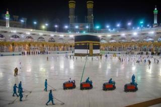 Workers clean while a few pilgrims pray in front of the Kaaba, Islam's holiest shrine, at the Grand Mosque complex in Saudi Arabia's holy city of Mecca on 27 July 2020