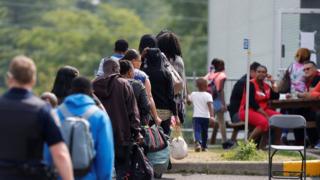Лица, ищущие убежища, ждут, пока их будут обрабатывать на перекрестке Квебек-Нью-Йорк