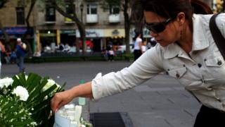 Mujer poniendo un ramo de flores para homenajear a los muertos.