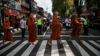 Buddhist monks walk across a street while collecting alms ahead of Vesak day in Magelang, Central Java, Indonesia May 28, 2018