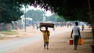 Africa, Southern Africa, Mozambique, Mueda, View Of Muslim Man Carrying Stack Of Firewood On His Head