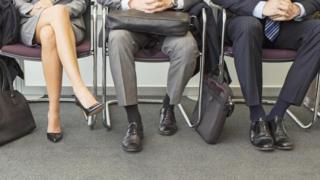 Piernas de personas sentadas esperando su turno para una entrevista de trabajo