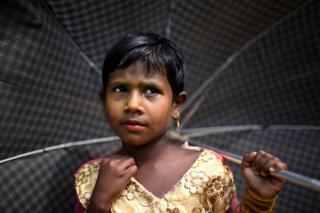   Refugee Rohingya Zinu Ara, 4 years old, poses for a photo while she carries camp ataka balukhali at Cox's Bazaar, Bangladesh 