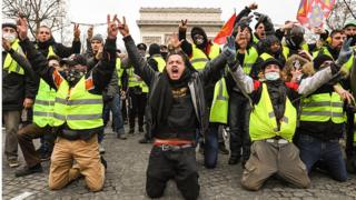Des "gilets jaunes" font le signe de victoire, face aux policiers.