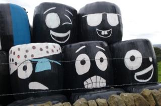 Faces drawn on hay bale covers