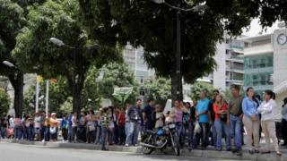 People queue to try to buy basic food items outside a supermarket in Caracas, Venezuela, April 28, 2016