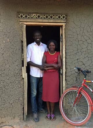 Herbat and Lucy standing in front of their house at Bidi Bidi