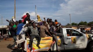Men ride on top of a vehicle during a primaries el