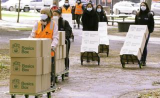 Una línea de trabajadores con máscaras entrega suministros de alimentos ordenados por el gobierno a una torre de viviendas cerrada en Melbourne