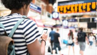 woman and phone on train platform