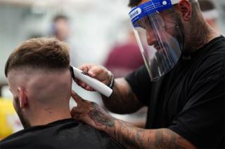 A man has his hair shaved by a hairdresser