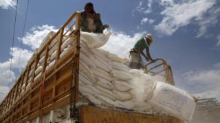 A worker stands on a vehicle carrying food and medical supplies provided by the World Food Program in Sanaa, Yemen