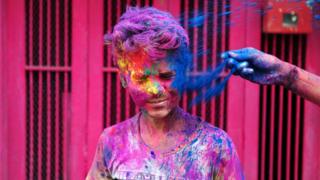 An Indian boy is covered with coloured paint powder