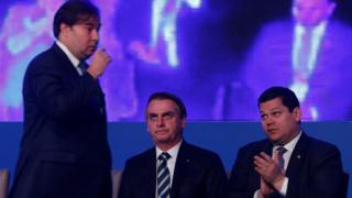 Rodrigo Maia passa por Jair Bolsonaro e Davi Alcolumbre durante cerimônia em Brasília em 9 de abril
