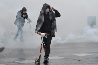 A protester stands among smoke during clashes with police in Nantes, western France