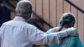 An Indian couple walk towards a hospital
