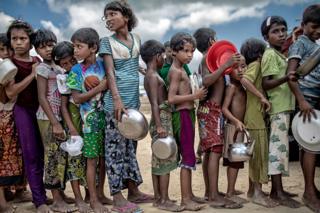 Children holding bowls queuing for food