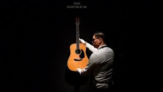 radnik u galeriji sa gitarom Dejvida Gilmora