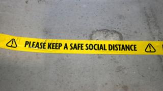Floor sign reminding of need to social distance