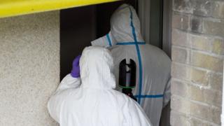Forensics officers enter the house