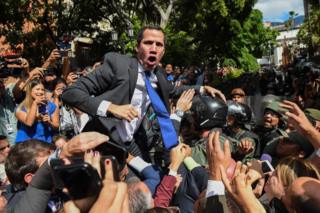Venezuelan opposition leader Juan Guaido shouts as he is surrounded by journalists