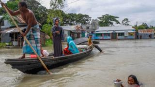 People ride on boat in flooded area after heavy monsoon rains in Dohrar near Dhaka, Bangladesh