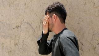 Mirwais Elmi cries covering his face