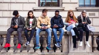 Teenagers looking at their phones (file photo)